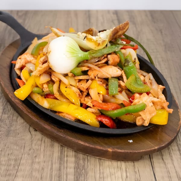 Sizzling chicken fajitas with colorful bell peppers and onions in a cast iron skillet.