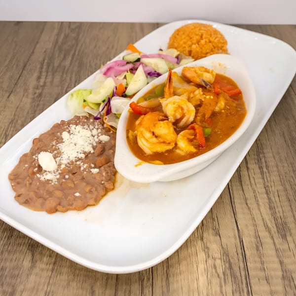 Shrimp in red sauce with rice, refried beans, and a side salad on a white rectangular plate.