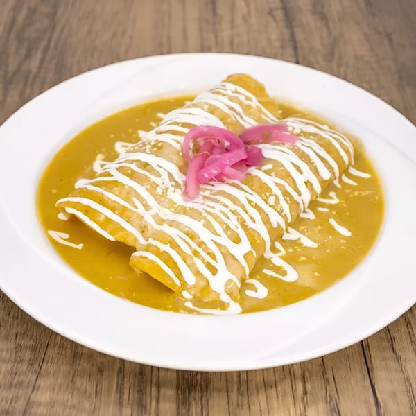Two enchiladas covered in green sauce, drizzled with sour cream, and topped with pickled red onions.