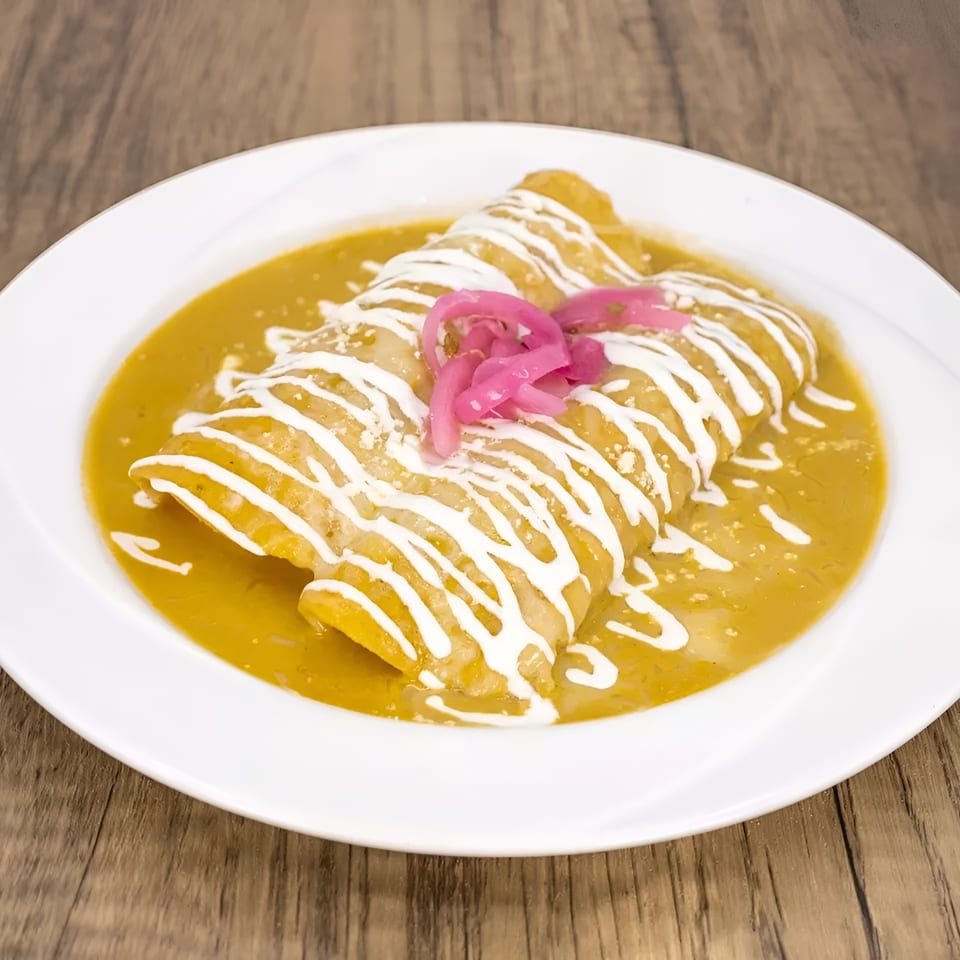 Two enchiladas covered in green sauce, drizzled with sour cream, and topped with pickled red onions.